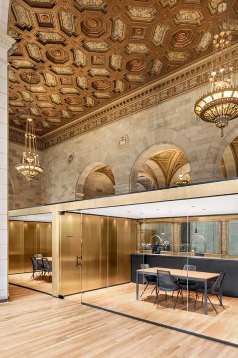 Custom retail in a historic building. This project highlights the art of layout within a historic setting. Modern modules have been seamlessly integrated into this classically designed space, creating a striking contrast between the old and the contemporary. Glass partitions framed in golden metal define functional zones while maintaining the openness and brightness of the space. Each module, designed to optimize volumes, combines practicality with aesthetics. The use of noble materials such as metal and glass blends harmoniously with the original architecture, delivering both an elegant structure and a work-conducive environment. The result is a high-end training facility where comfort and functionality intersect, all while honoring the architectural heritage of the building.