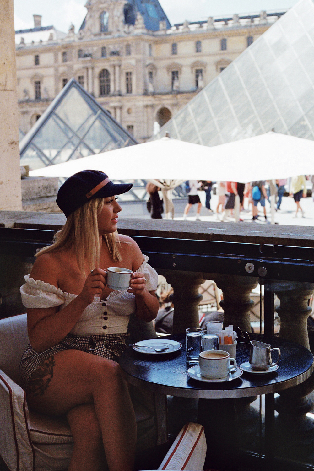 girl drinking coffee in a cafe overlooking Louvre Pyramid captured on film