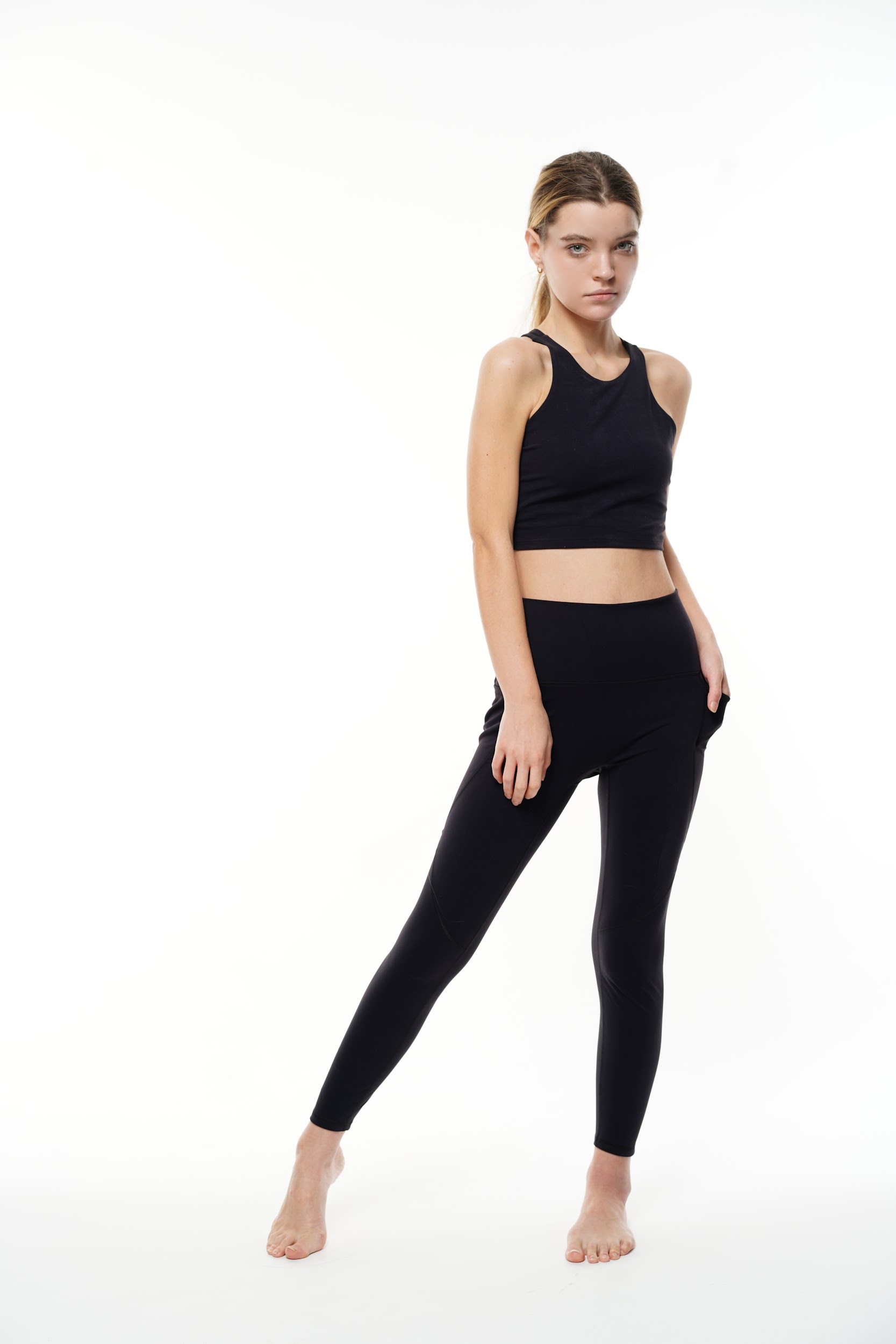 Model in sports leggings and tank top posing in Paris studio for e-commerce catalog