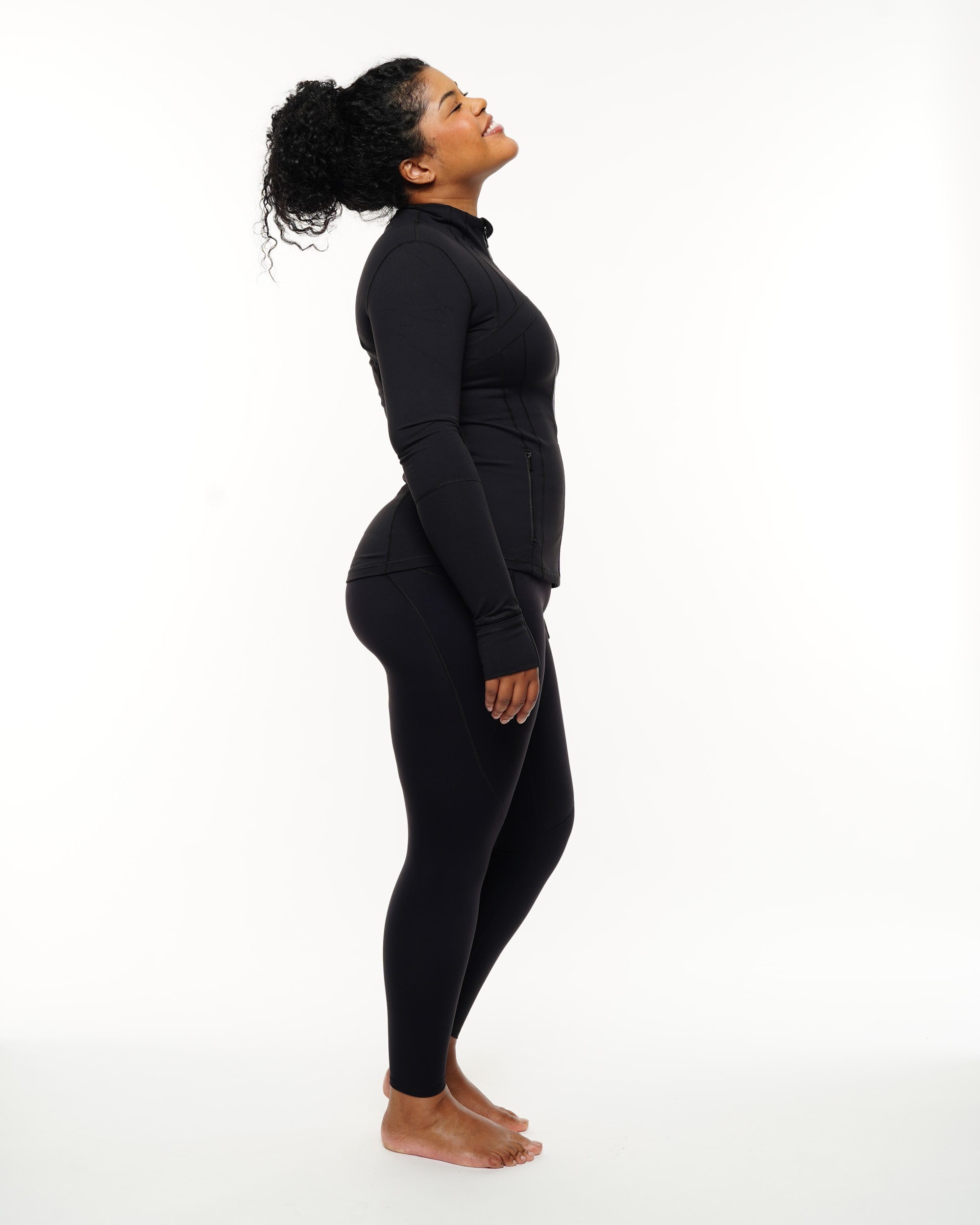 Side profile of a plus-model in sleek workout gear under studio lights by photographer Anya Parsley