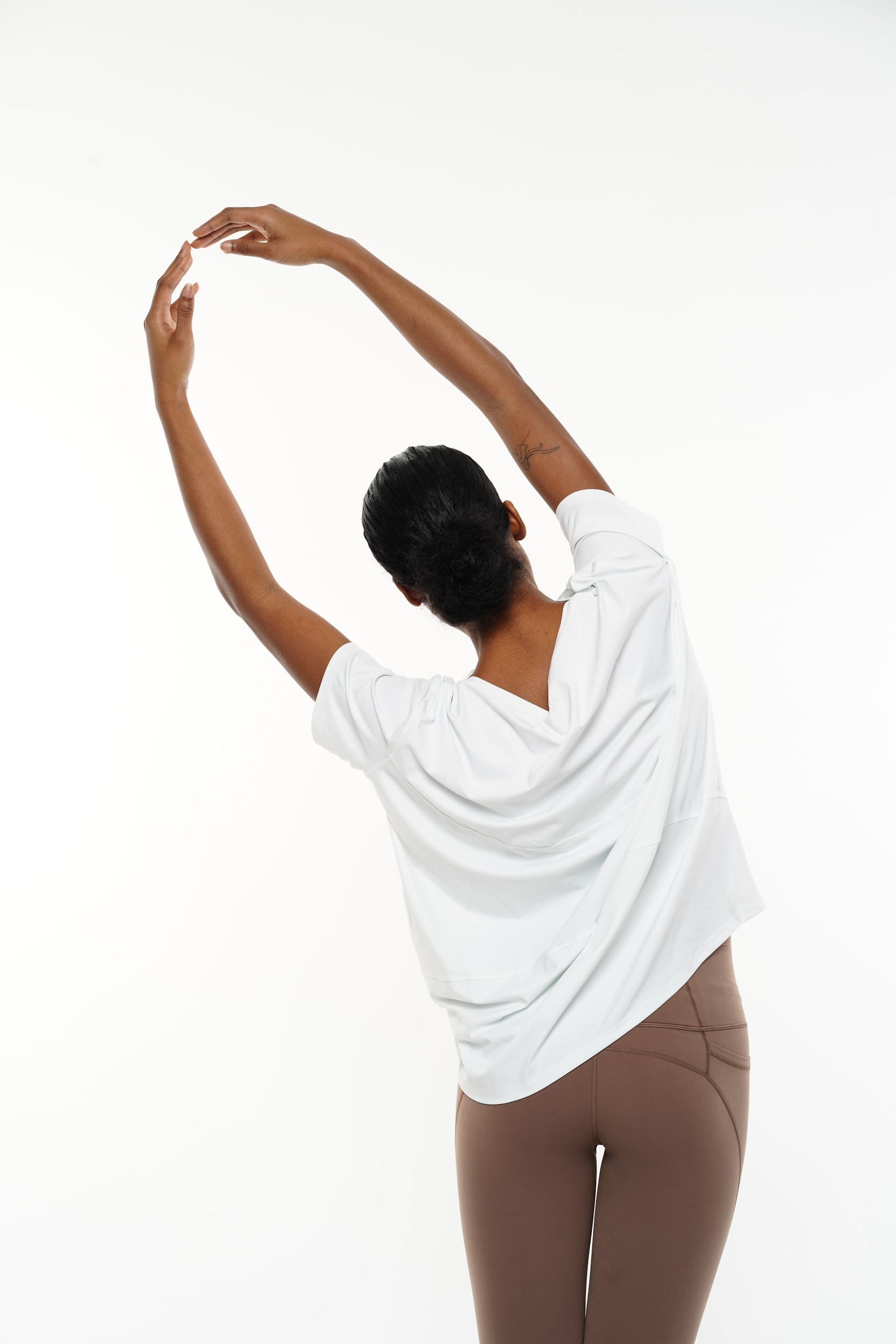Model in yoga outfit demonstrating flexibility on a white backdrop.
