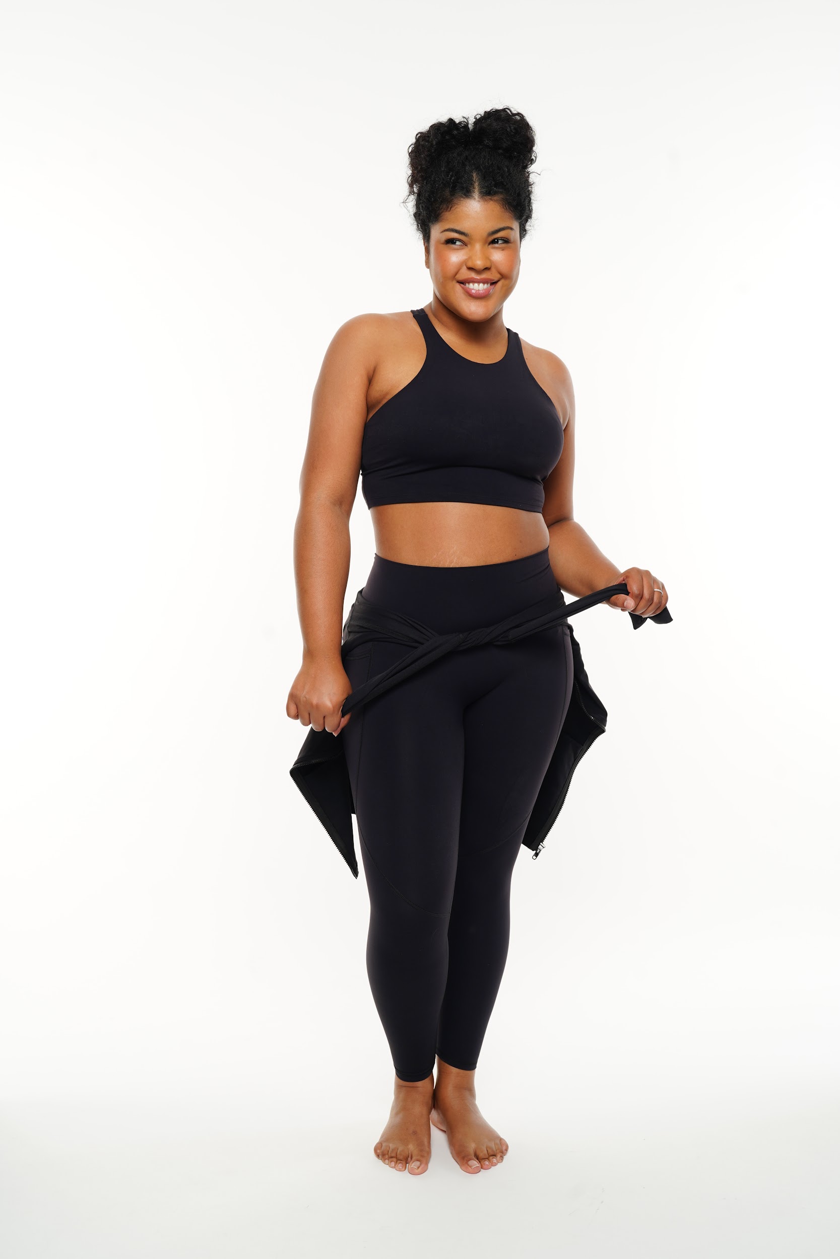 Plus-size model in a dynamic pose wearing athletic apparel in a Parisian photo studio.
