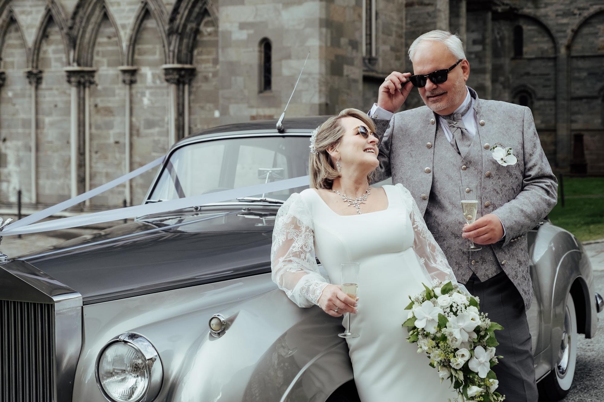 voksen brudepar står ved en vintage rolls royce nær Nidarosdomen.