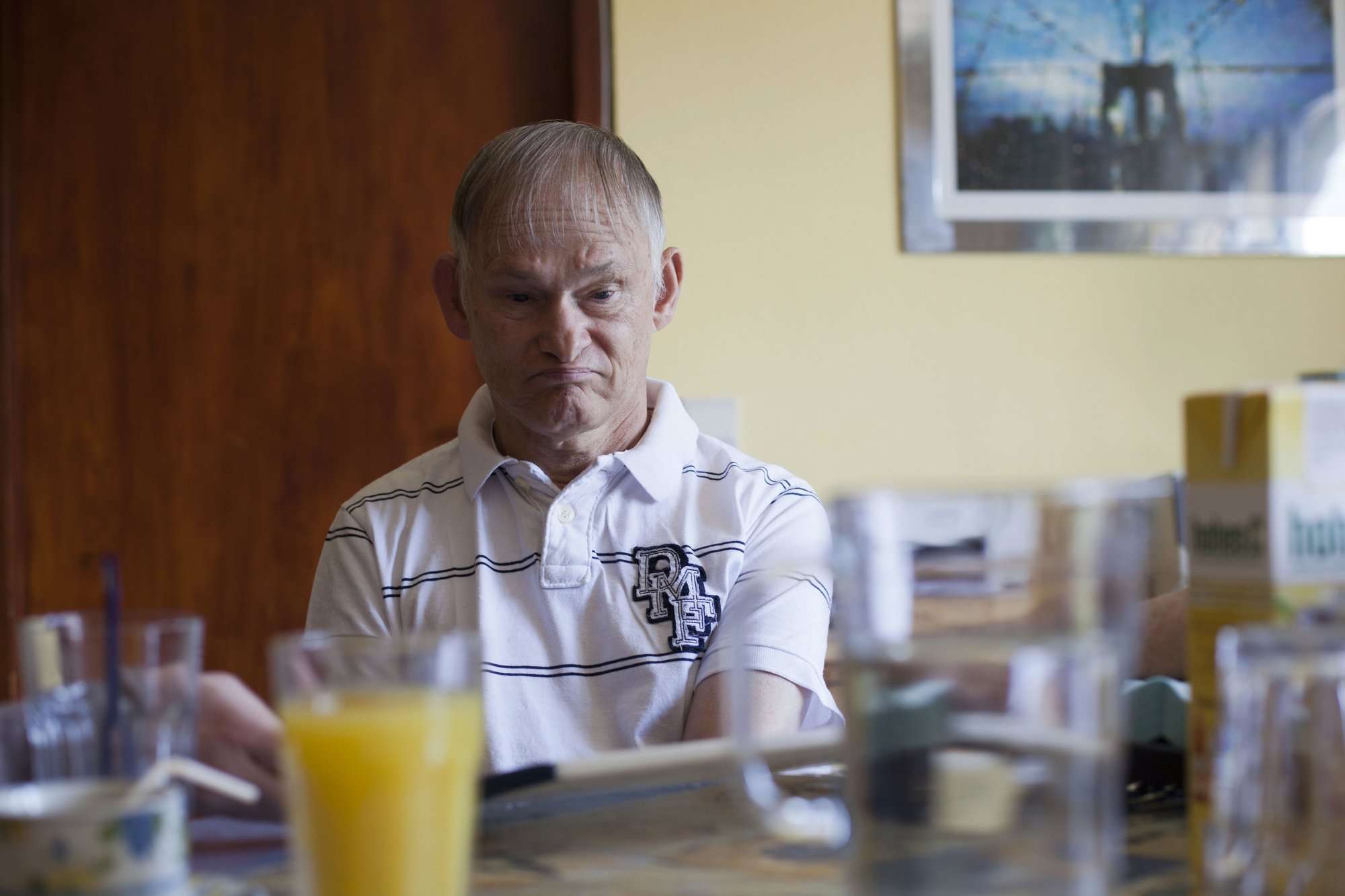 Portrait von einem Mann mit Behinderung, der in seiner Wohnung frühstückt