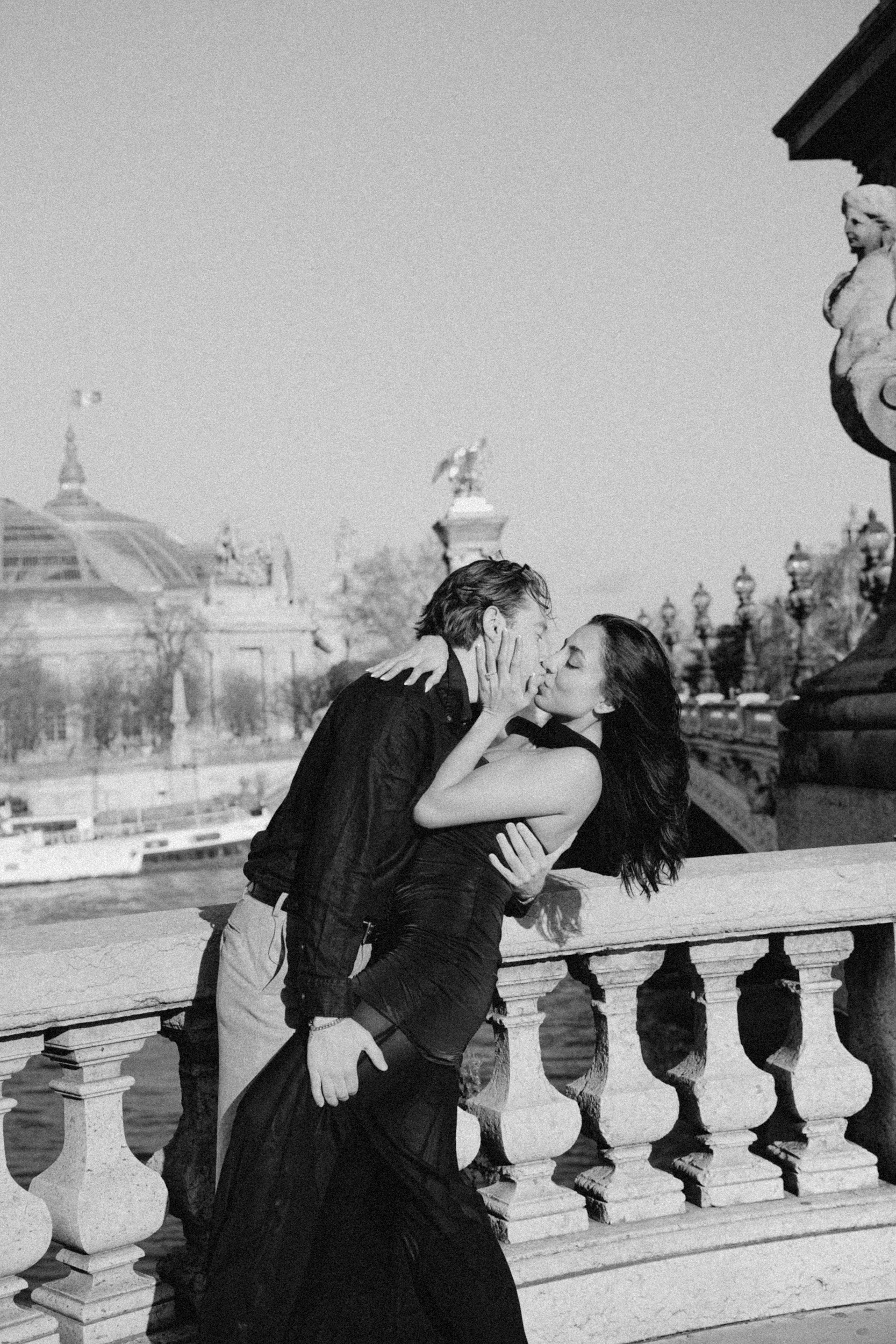 Artistic black and white photo of a couple kissing on the bridge Pont Alexandre III in Paris