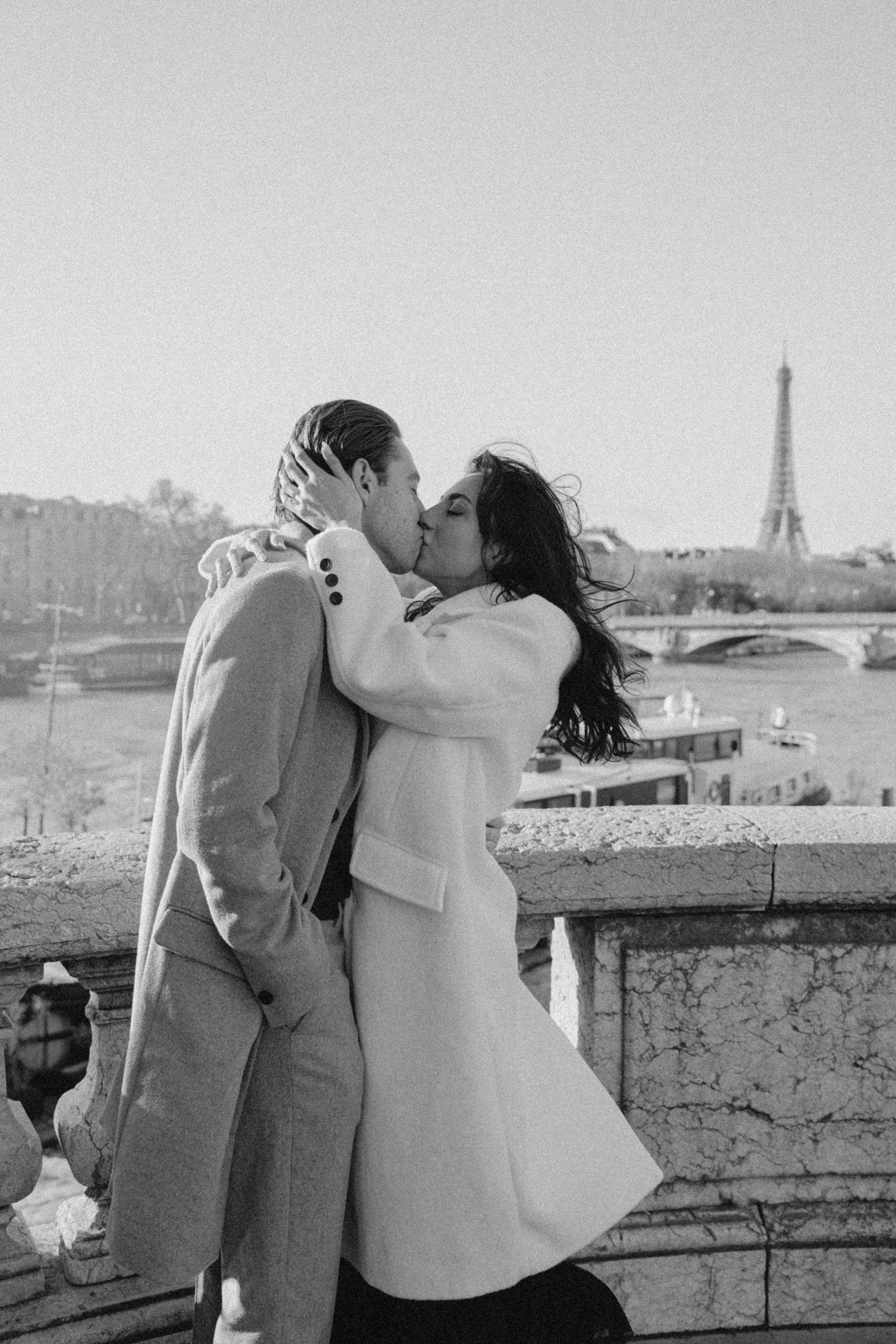Romantic black and white photo of a couple's kiss with the Eiffel tower in the background