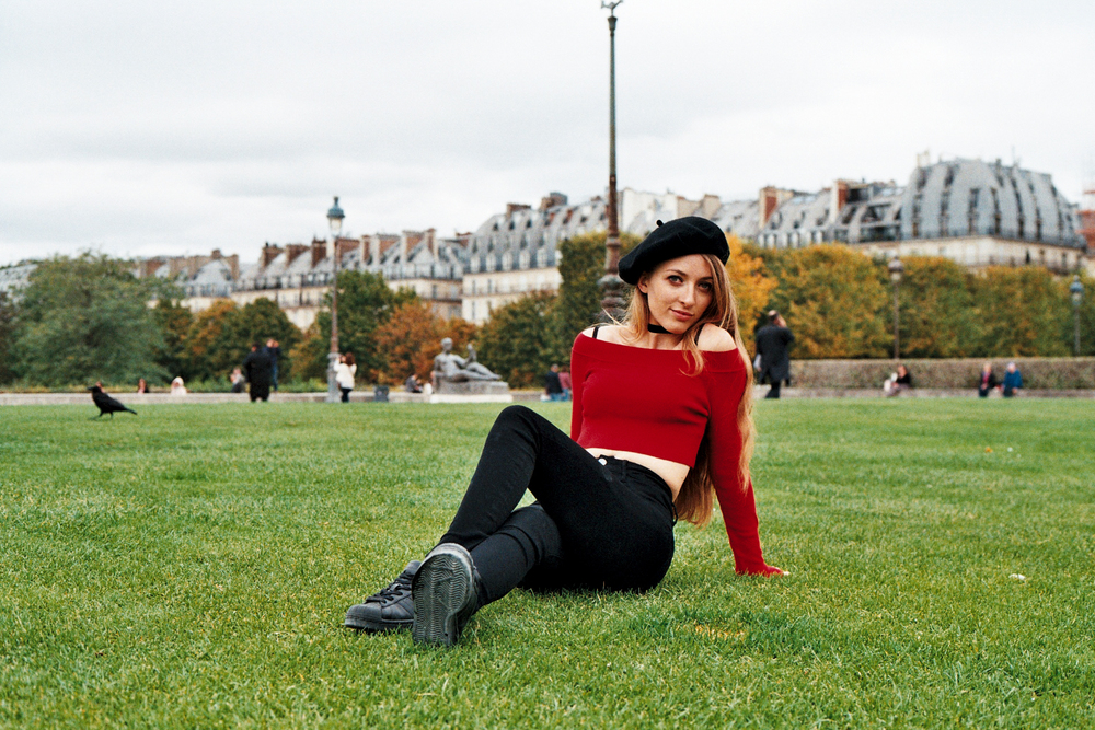 film portrait of a woman wearing a beret and sitting on the lawn of Tuileries garden taken by Anya Parsley