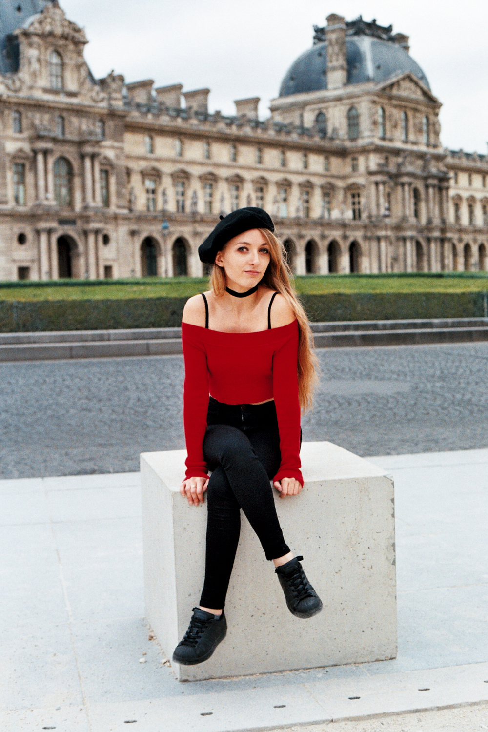Young woman in vintage beret posing in front of the Louvre, Paris