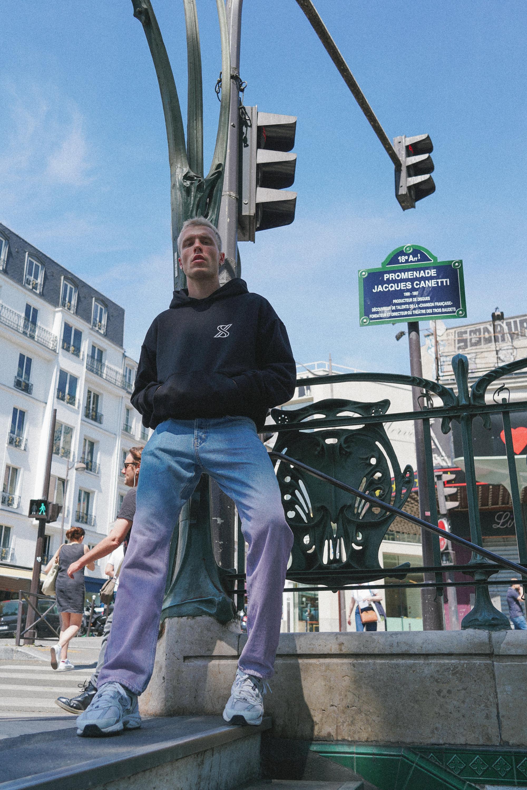 Male model in SNATCH hoodie at vibrant Pigalle street scene in street style Paris