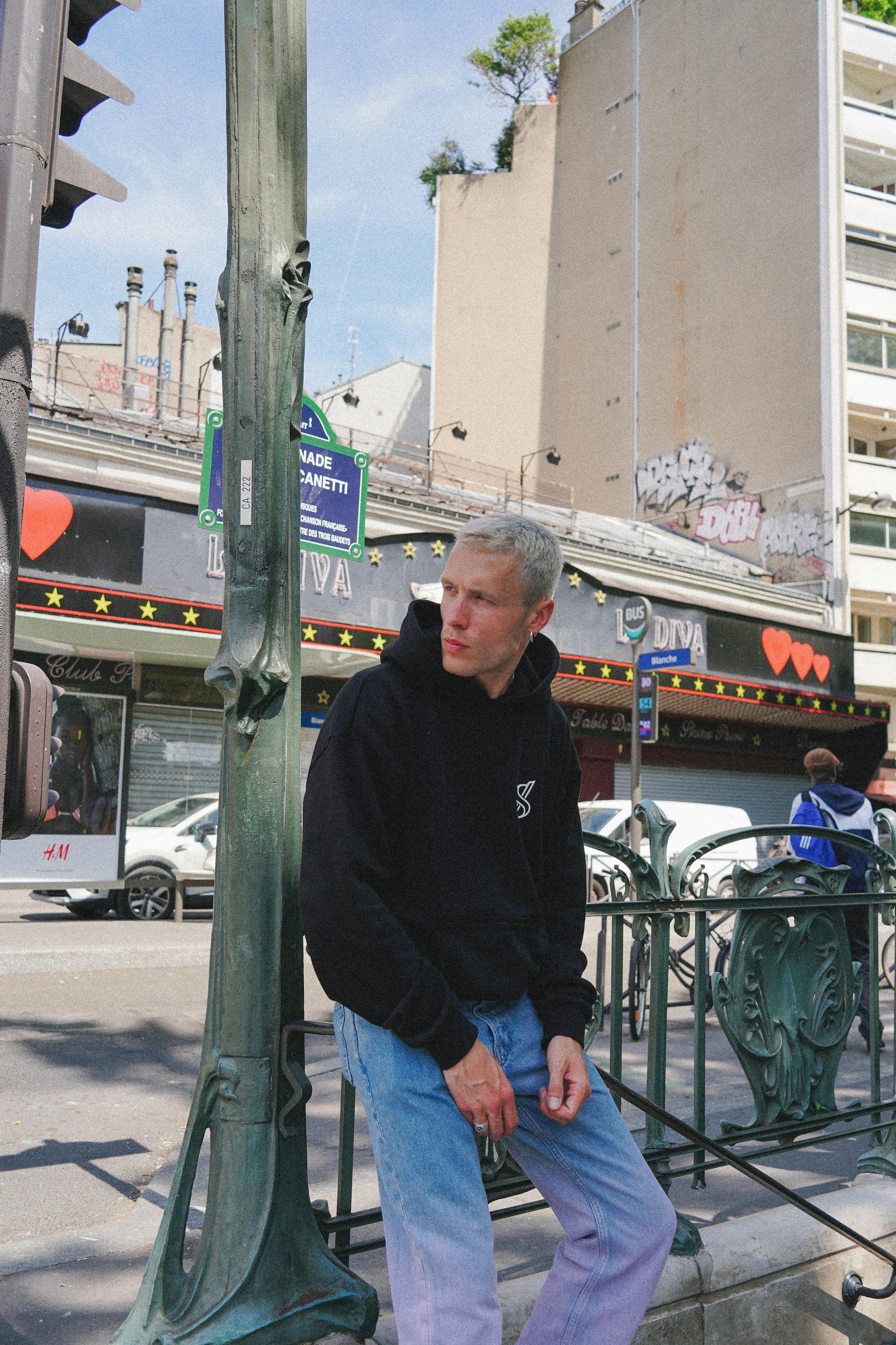 Male model in SNATCH hoodie at vibrant Pigalle street scene during a street style fashion photoshoot