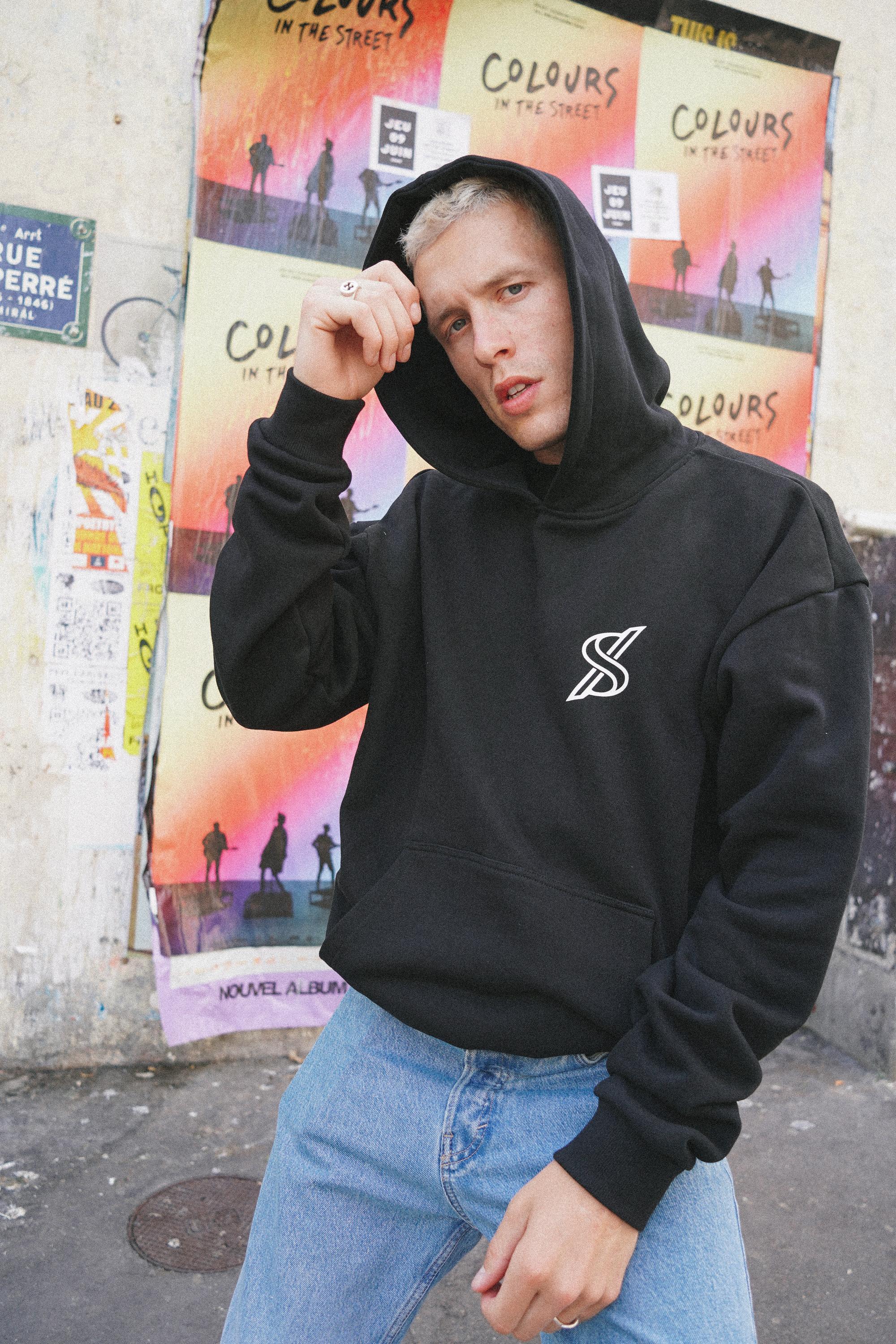 Male model showcasing SNATCH streetwear in front of graffiti wall by Paris street style fashion photographer