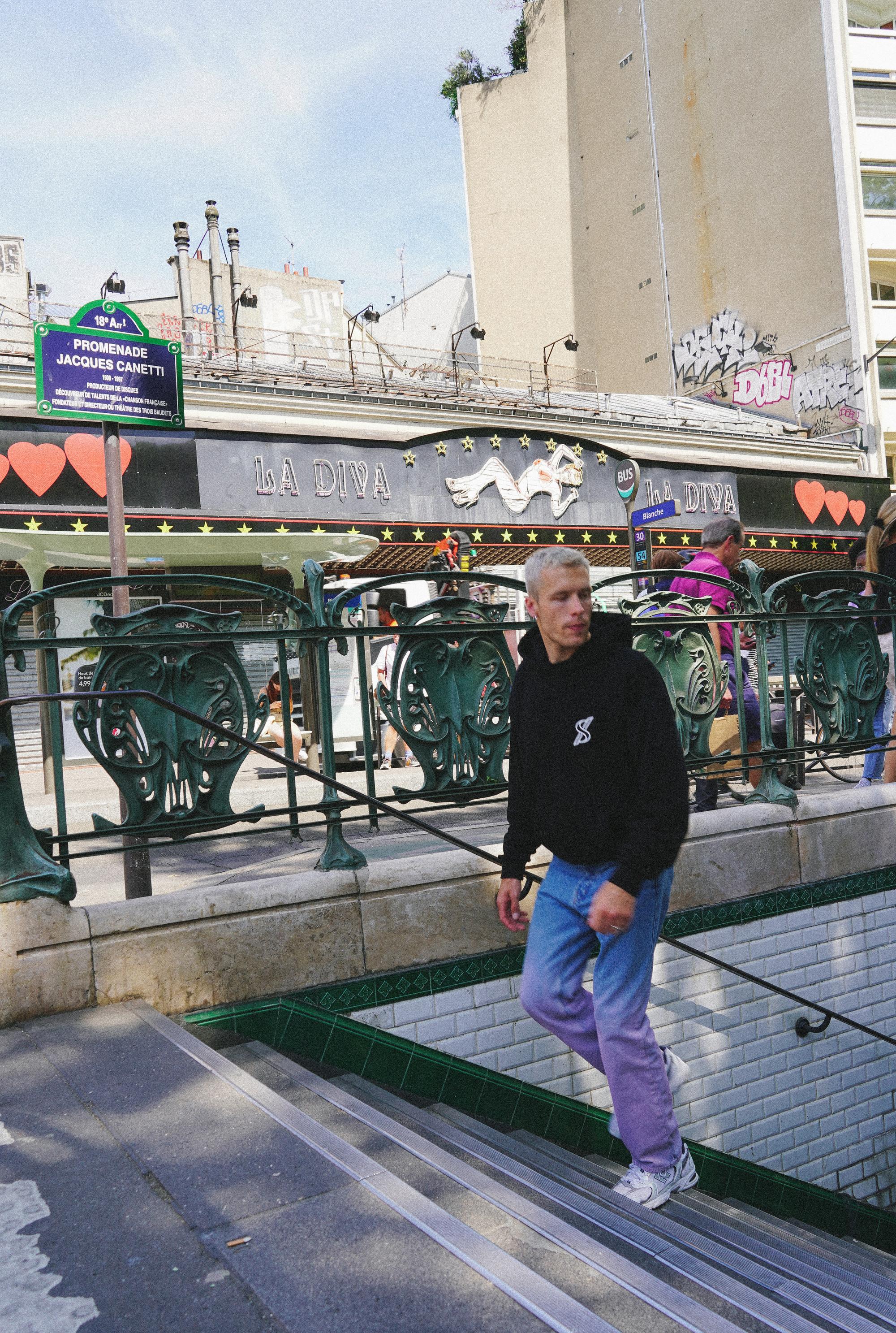 Male model in SNATCH hoodie at vibrant Pigalle street scene by Paris street style photographer Anya Parsley