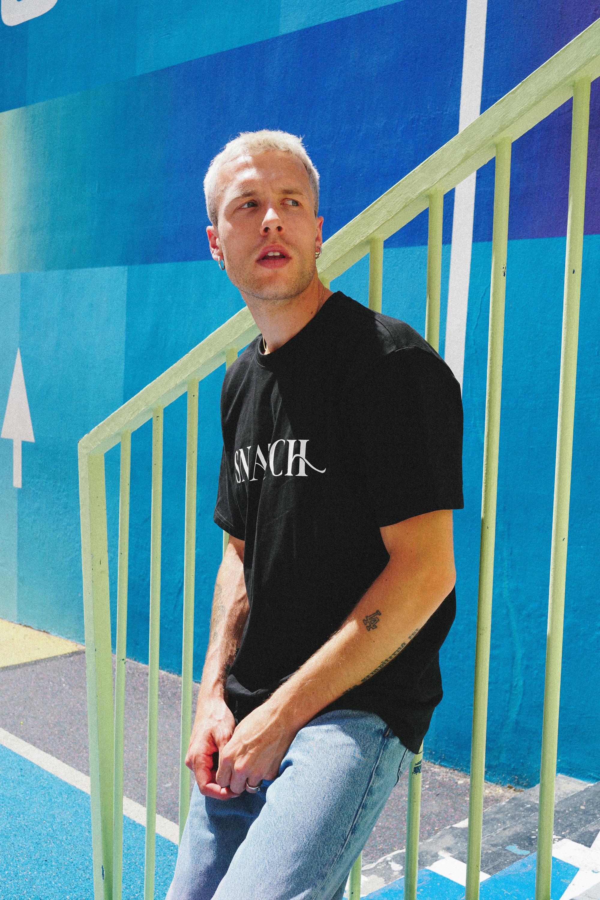 Male model showcasing SNATCH t-shirt at Duperré basketball court in Pigalle during a Street Style photoshoot in Paris