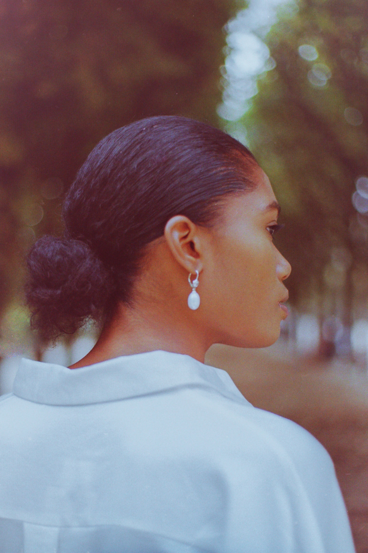 Pearls jewelry displayed on a model  against Palais Royal garden backdrop during a lookbook photoshoot in Paris