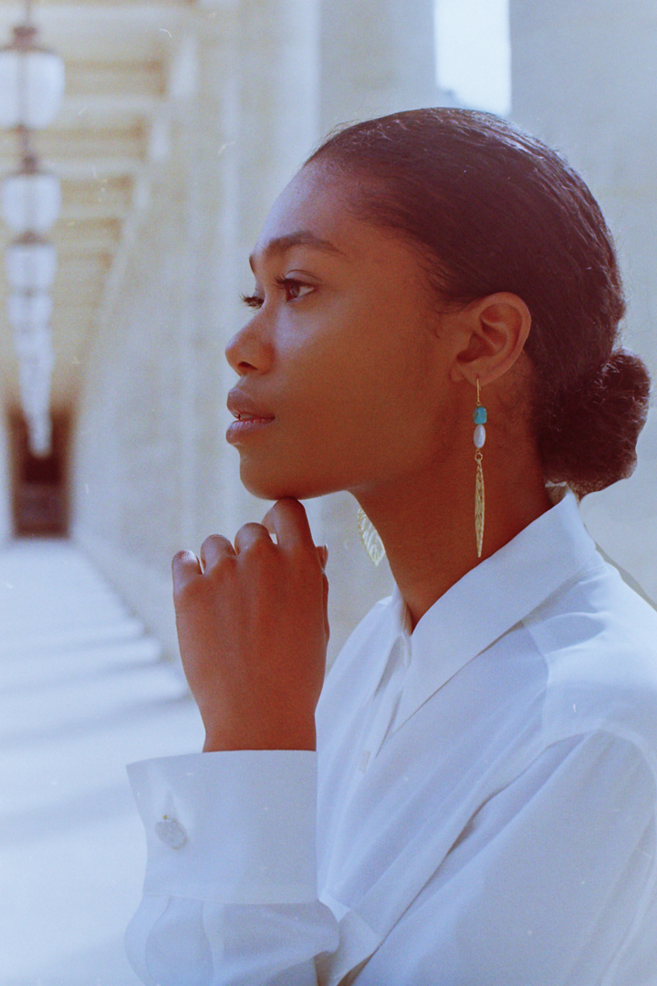 charming analog photo of a model wearing earrings with pearls during a lookbook photoshoot in Palais Royal Garden in Paris