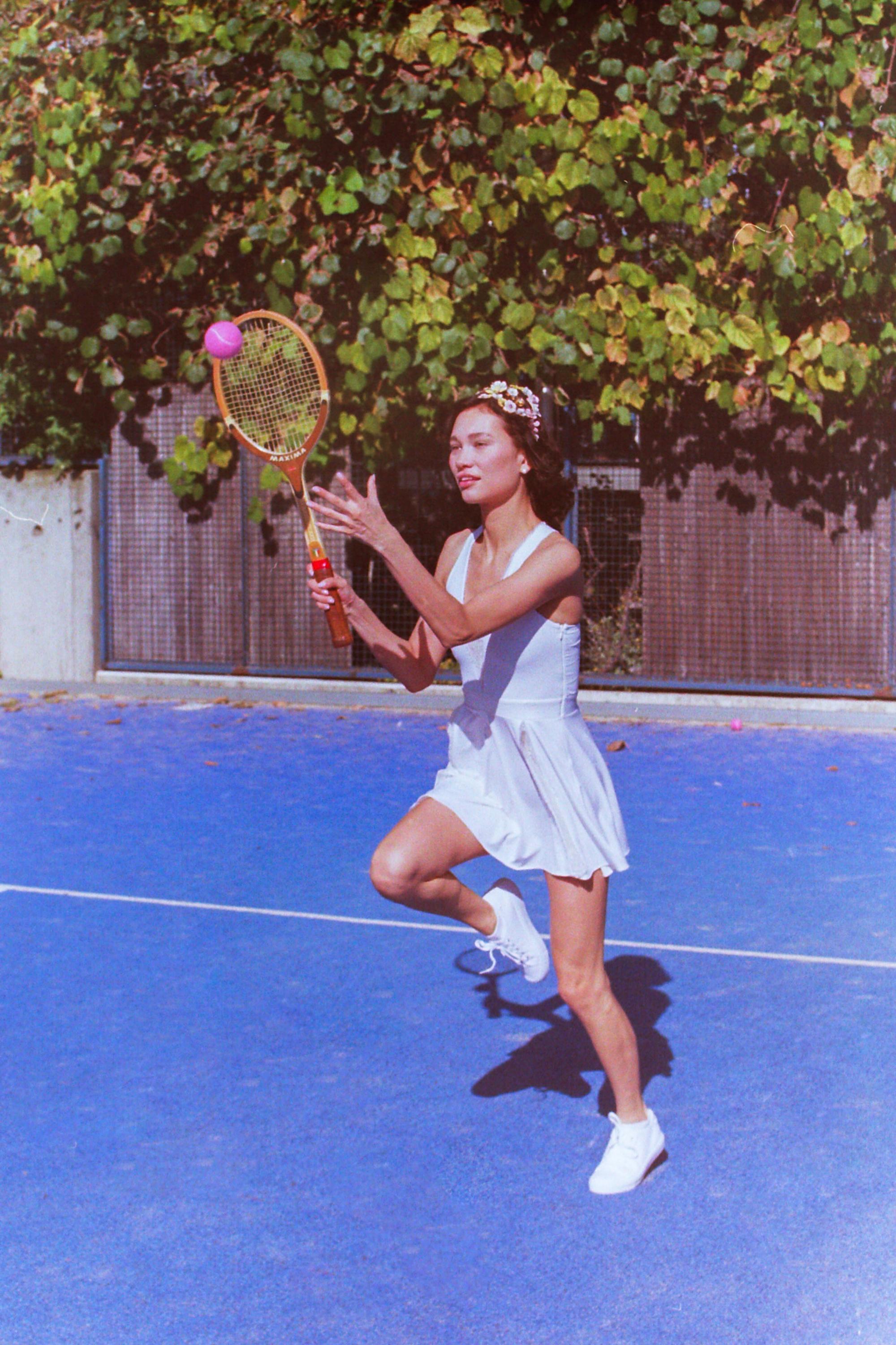 Model posing in Thaber's retro tennis outfit at Parisian blue tennis court, captured on film by Anya Parsley, fashion photographer