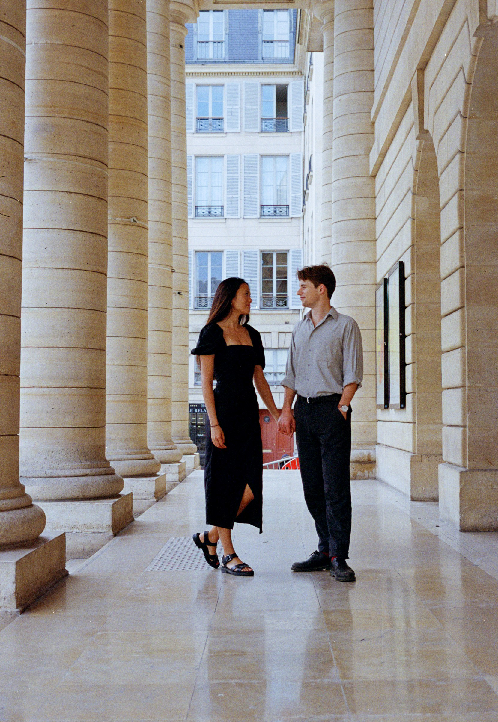 Couple holding hands with a historical architecture backdrop during their engagement photo shoot in Paris