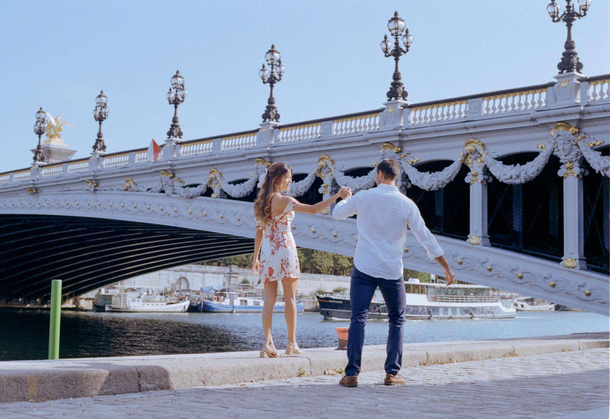 charming engagement photo of a couple holding hands in Paris by the bridge Alexandre III