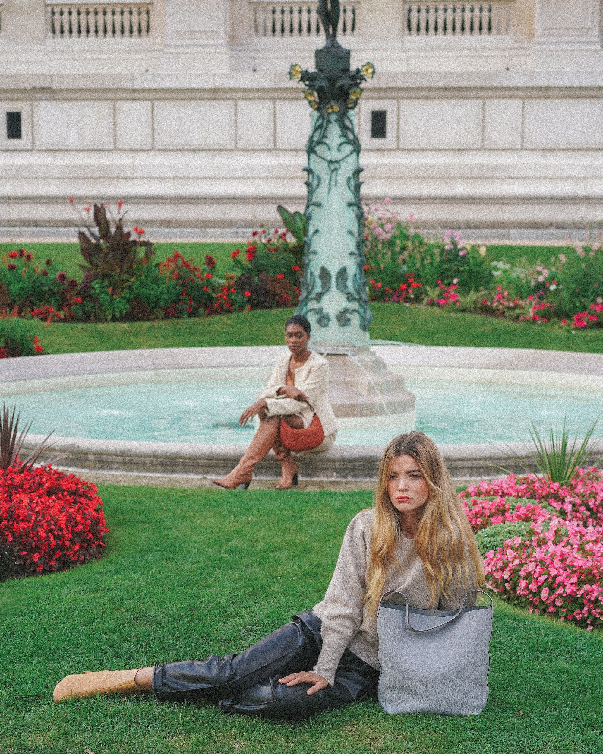 Two models showcasing H.Pai bags in a vibrant garden in Paris